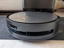 Ecovacs Deebot X9 Pro Omni robot vacuum with 9.8 cm flat design and visible dust marks on black surface