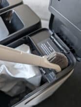 View of the MOVA Z50 Ultra Station with cleaning brush in the vacuum cleaner bag compartment, showing a well thought-out storage solution for maintenance accessories